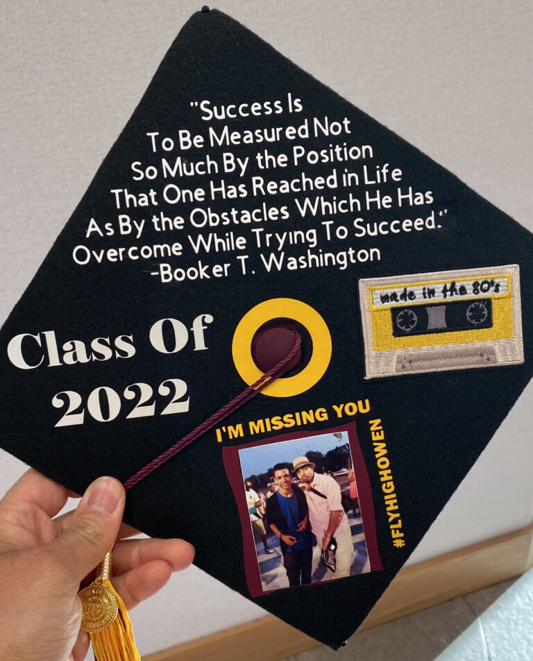 A decorated mortarboard that says "Success is to be measured not so much by the position that one has reached in life as by the obstacles which he has overcome while trying to succeed." - Booker T. Washington. Class of 2022. There is a photo of the grad and a relative with the words "I'm missing you," the hashtag #FlyHighOwen and a cassette tape labeled "Made in the 80s."