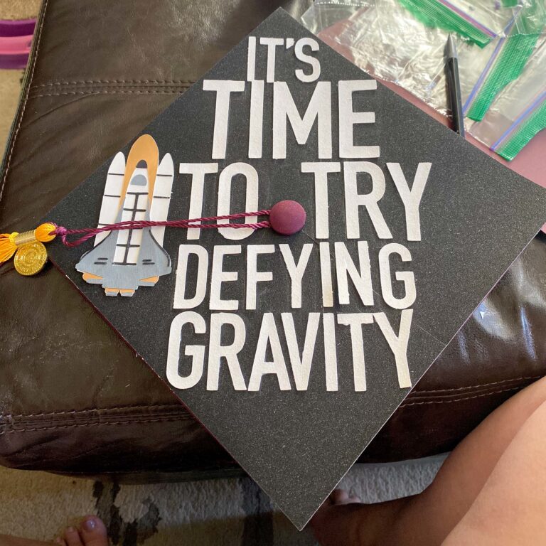 A decorated mortarboard with the space shuttle and the words: It's time to try defying gravity.