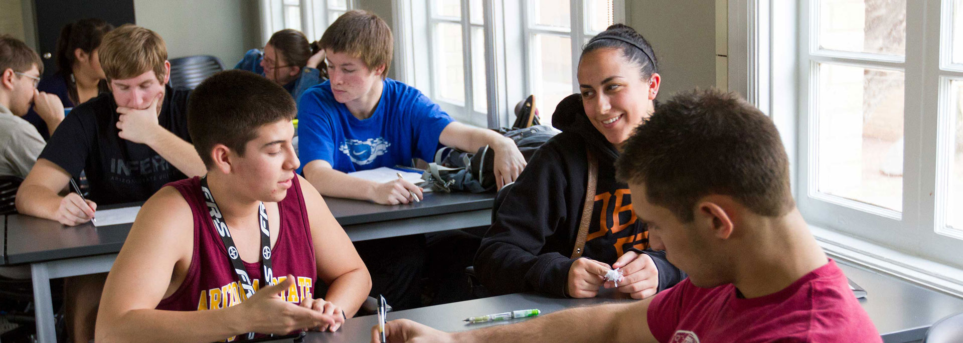 A couple of students work at a table together with an undergraduate teaching assistant