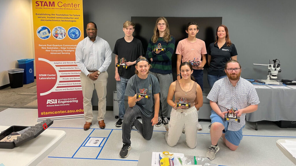 A group of students and faculty member Michel Kinsy pose with devices in the STAM Center.