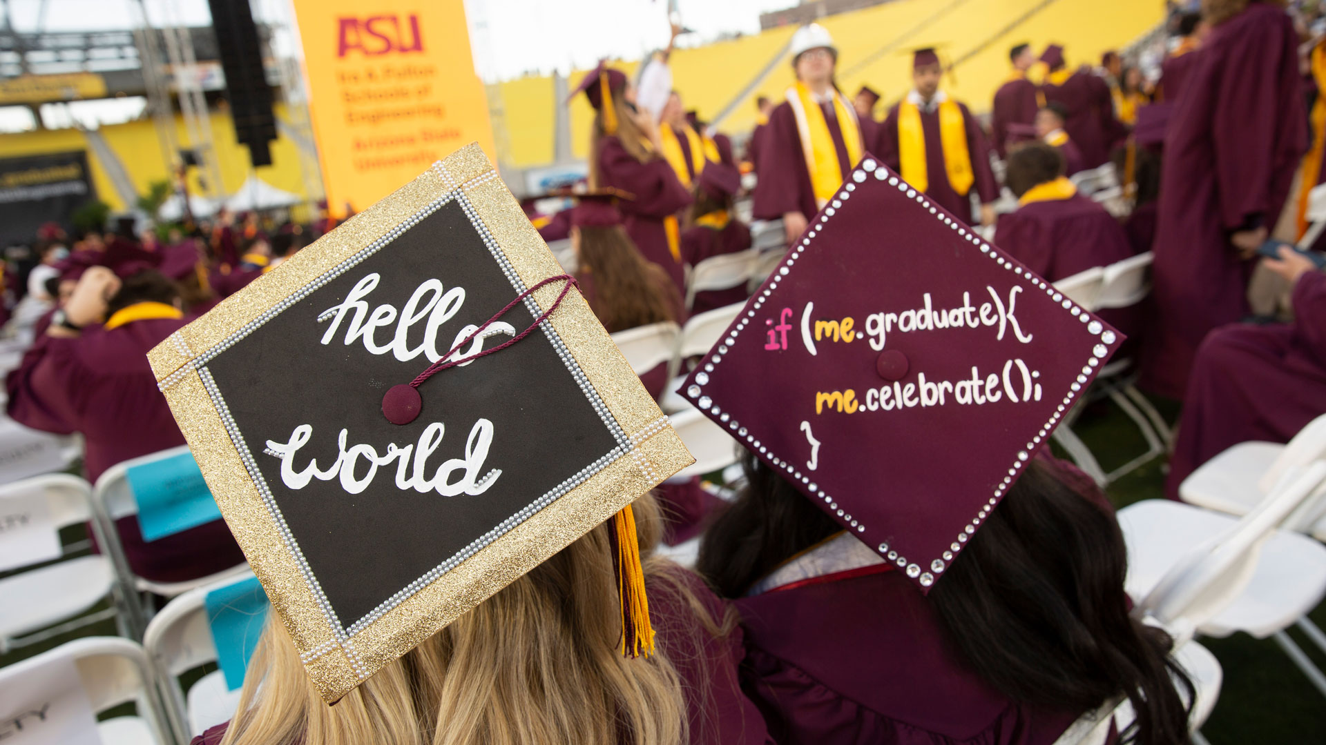 Two decorated mortarboards at Fulton Schools Convocation that say "hello world" and "if (me.graduate){me.celebrate();}