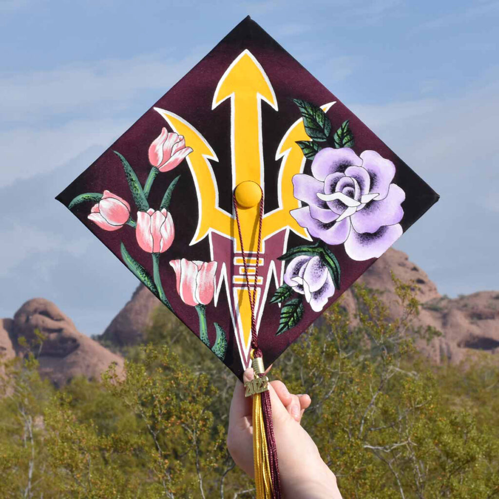A decorated mortarboard by Aisling Martin, engineering management BSE, that has a painted pitchfork and flowers.