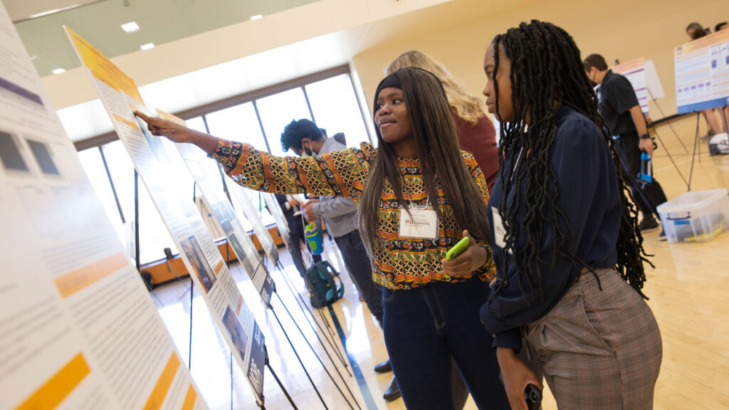 Two students look at a research poster.