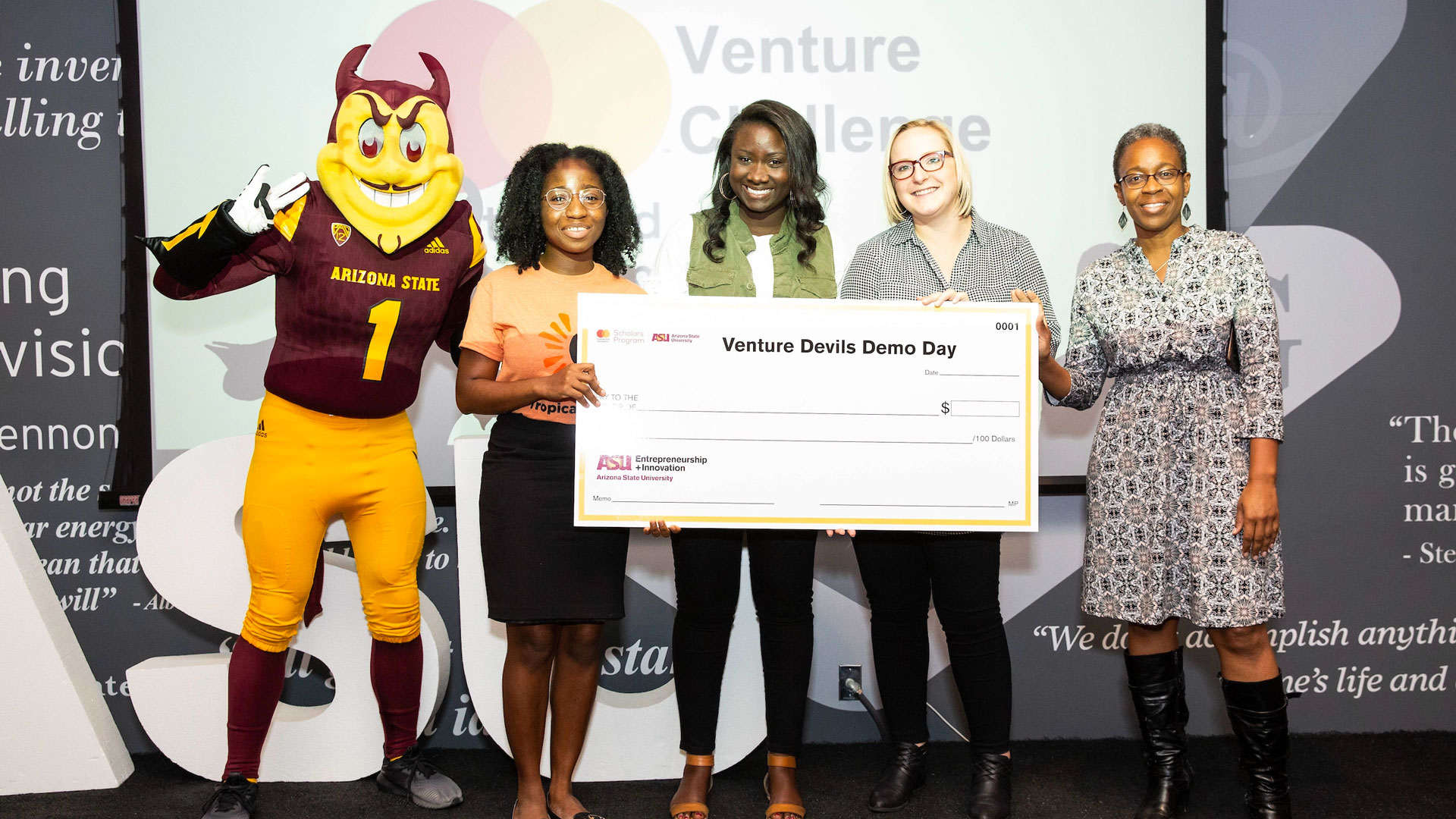 Student entrepreneurs pose with Sparky and a big check.