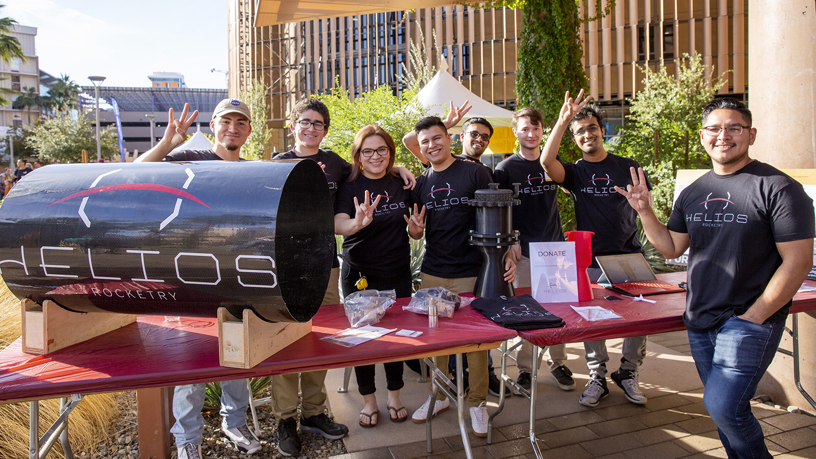 Helios Rocketry student organization members pose at a Homecoming Block Party table.