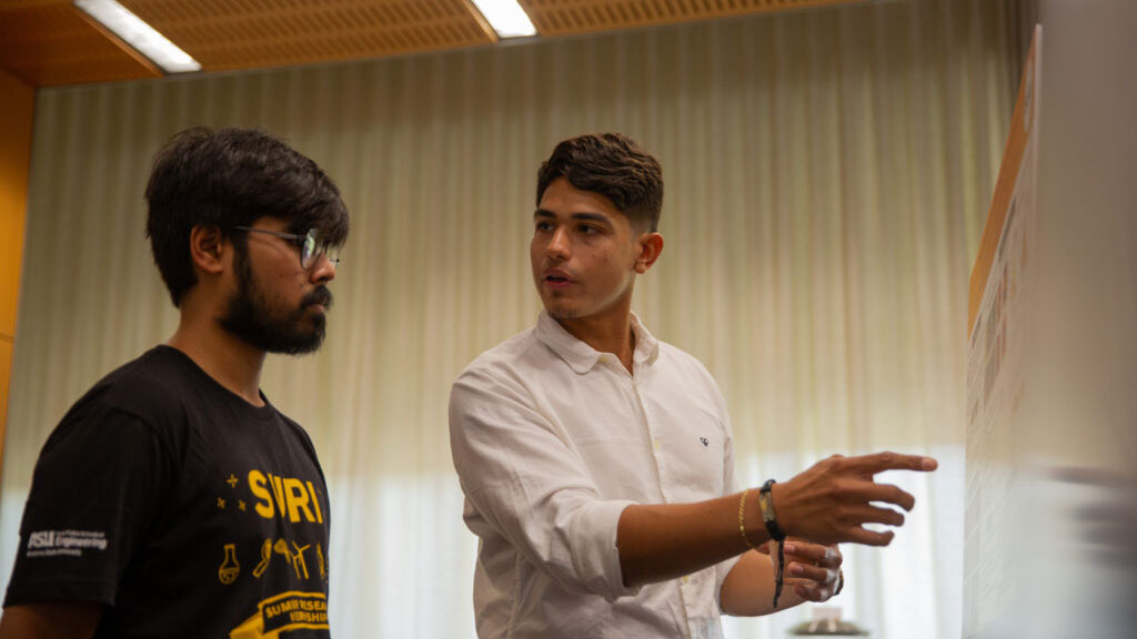 A SURI researcher displays his poster for someone else.