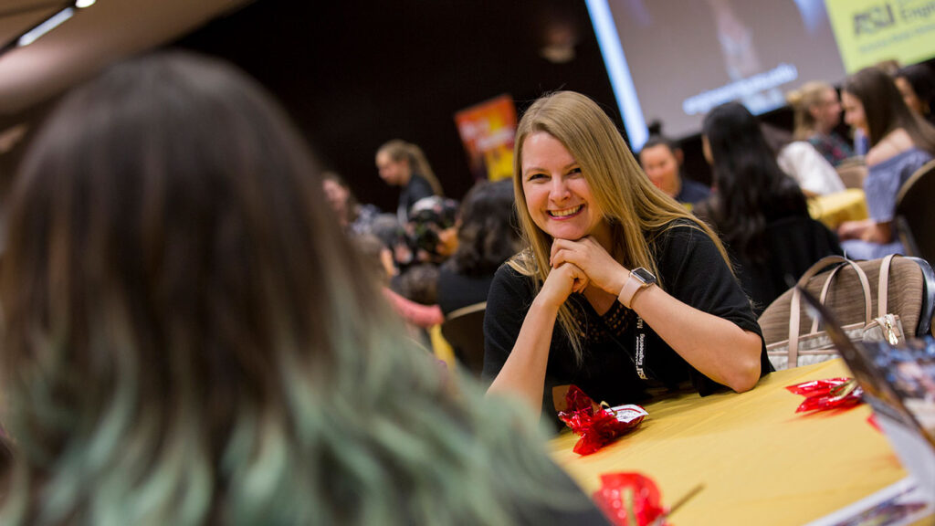 Two women sit across from each other and talk at Dinner with the Deans.