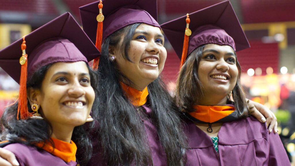 Three graduating students in caps and gowns.