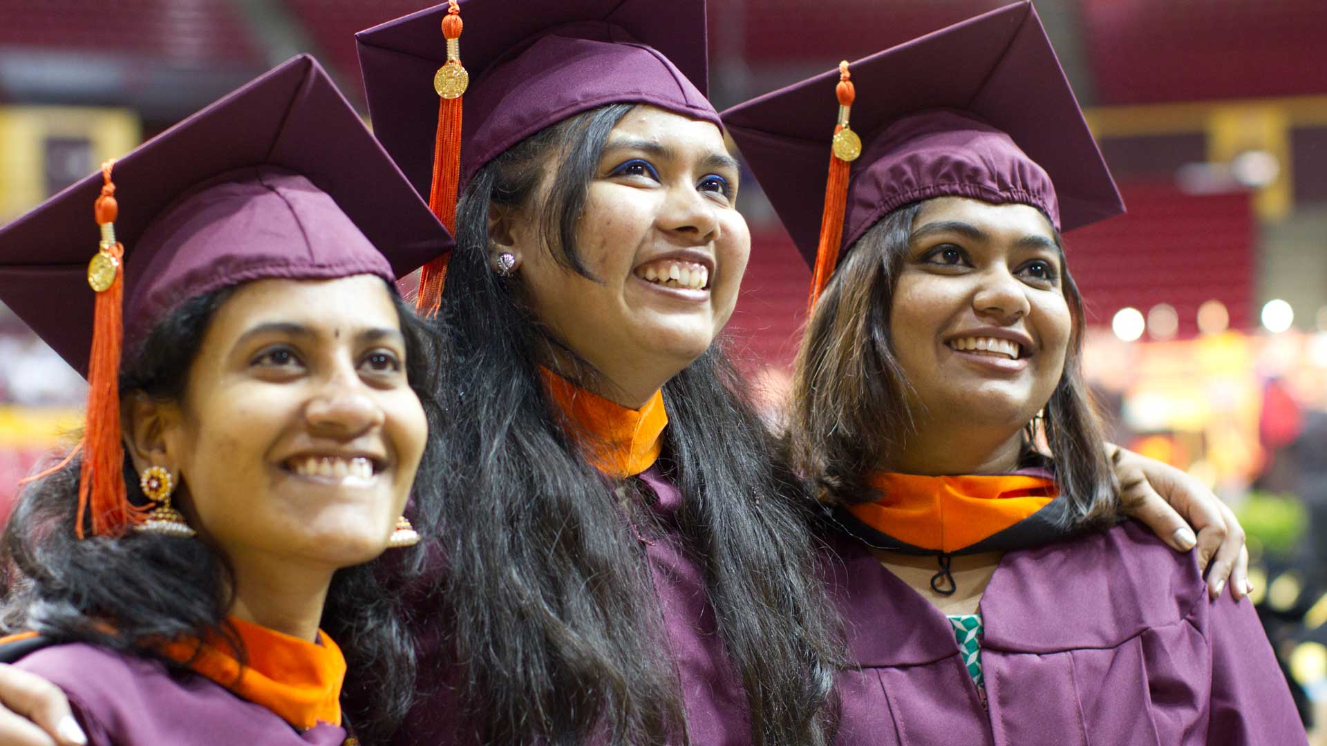 Three graduating students in caps and gowns.