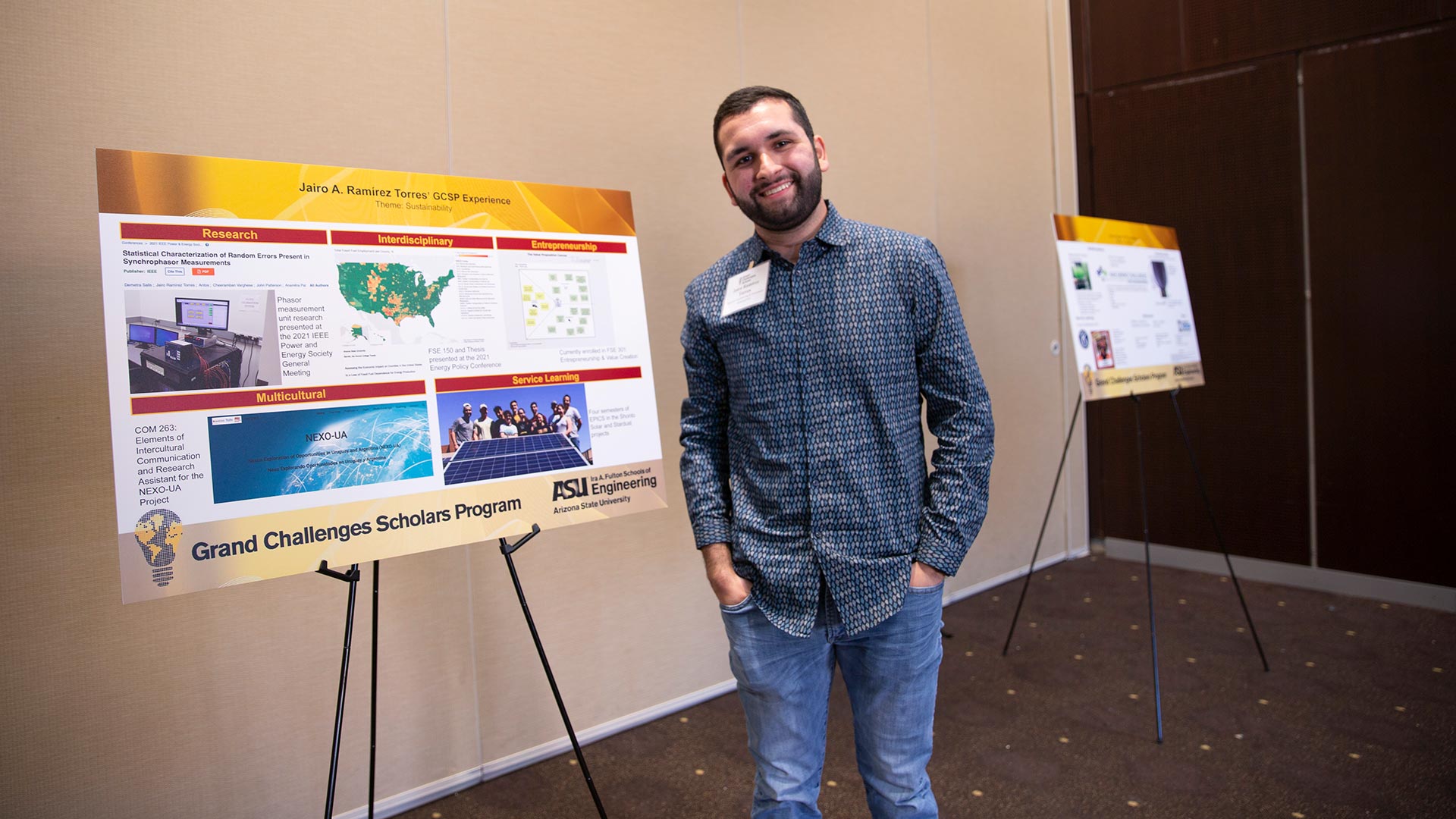 Male engineering student standing next to his research project poster.