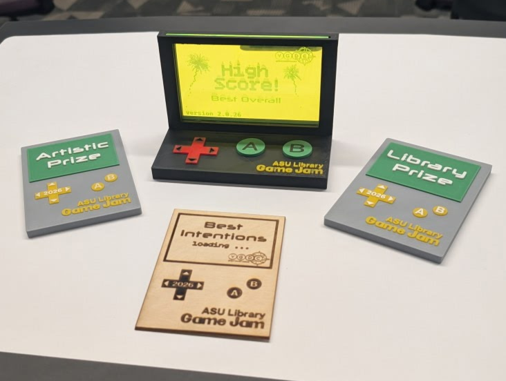 The prizes for the ASU Library Game Jam, including one for best overall, one artistic prize and a library prize. They are made to look like handheld gaming systems.