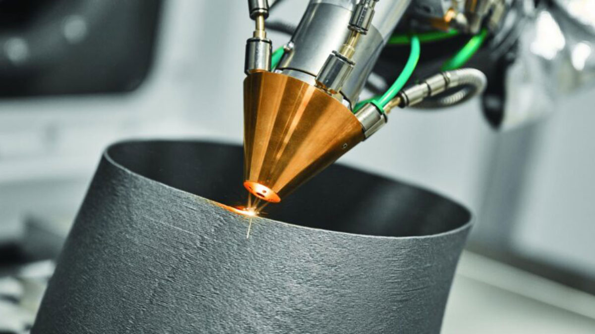 A metallic, conical nozzle emits a bright spark onto a cylindrical black object below.